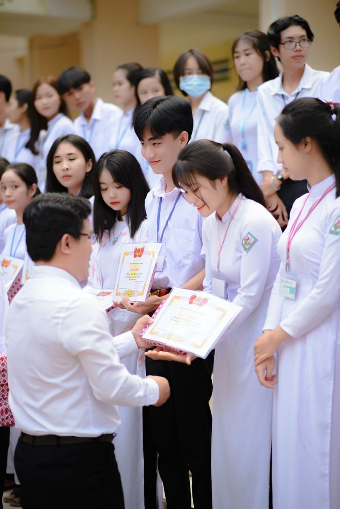 Services Group of Asian students receiving certificates during a graduation ceremony indoors.