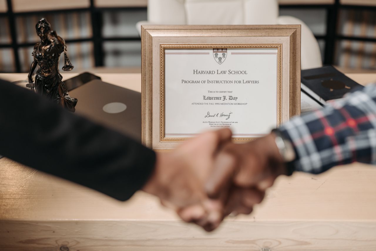 Services Harvard Law School degree with handshake representing achievement and professional agreement.