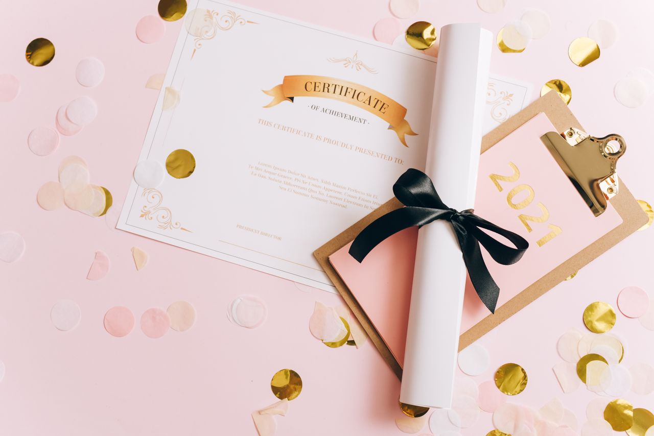 Services A rolled-up diploma with a certificate of achievement surrounded by confetti, perfect for graduation themes.