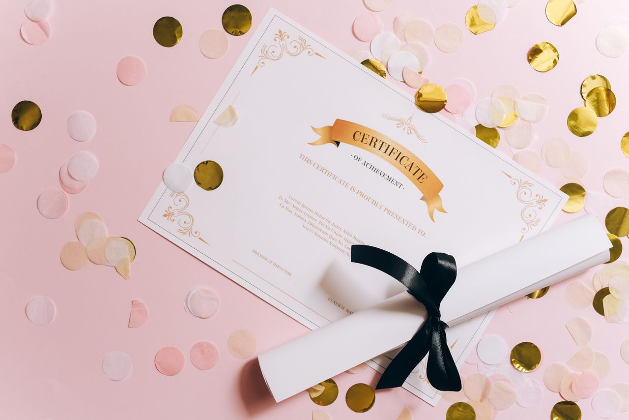 Services Certificate of achievement and diploma roll with ribbon on a pink confetti background.